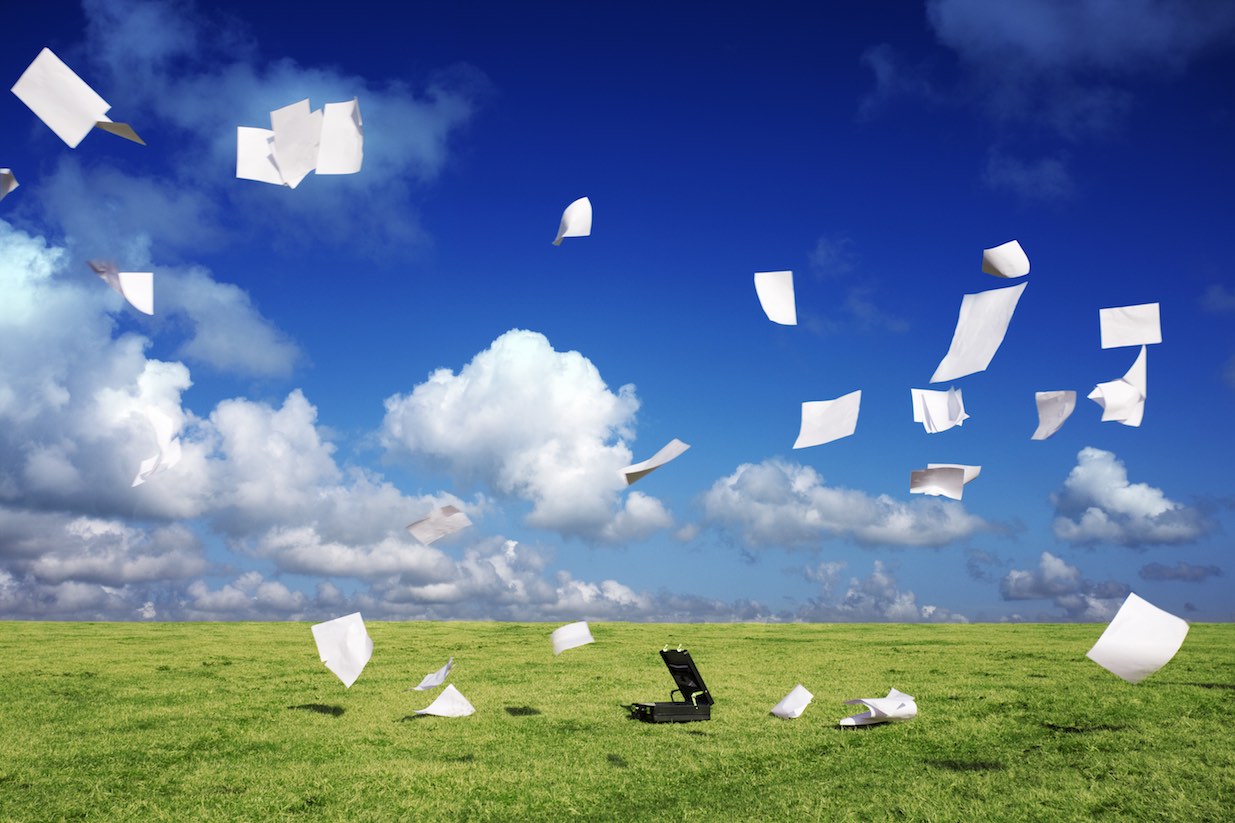 Briefcase on windy moorland with paper blowing away